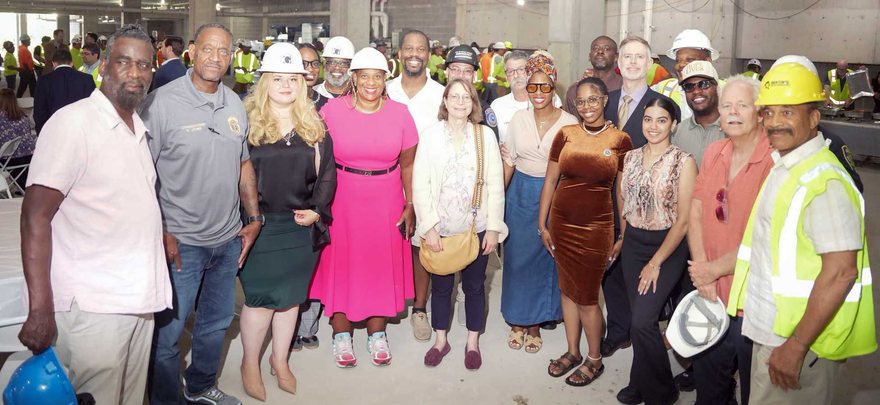 Mayor Shawyn Patterson-Howard, in pink, with officials and construction workers at the Opal 115 topping-off ceremony inside the unfinished building.